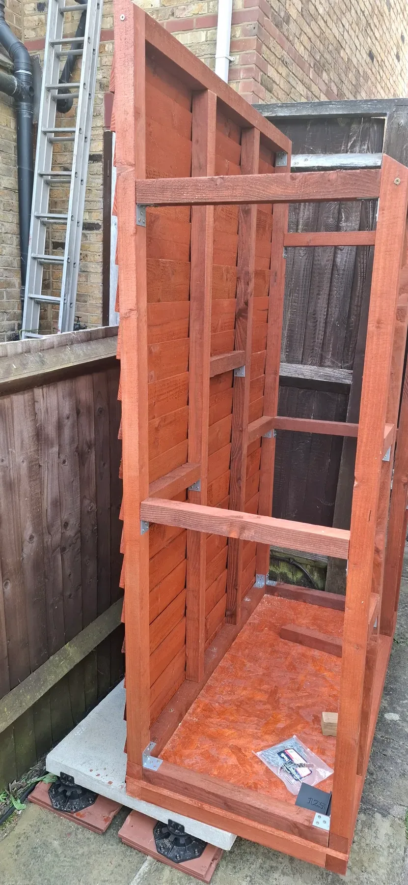 The sloped roof panel with slats attached, standing the frame upright